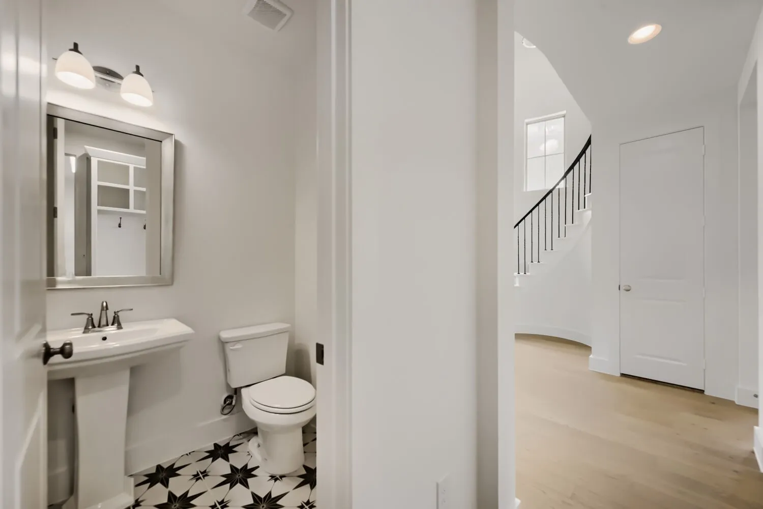 Pedestal sink with a coordinating toilet, framed mirror, and two-light vanity fixture