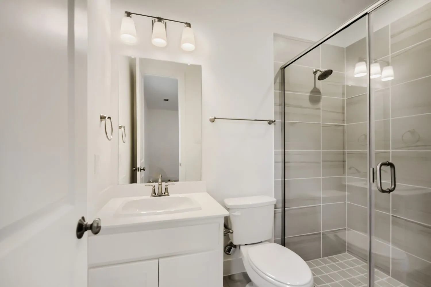 Bathroom featuring a glass-enclosed shower with large format wall tiles and a mosaic floor