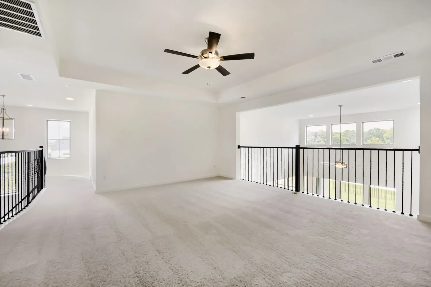Spacious loft area featuring light gray carpeting and a tray ceiling