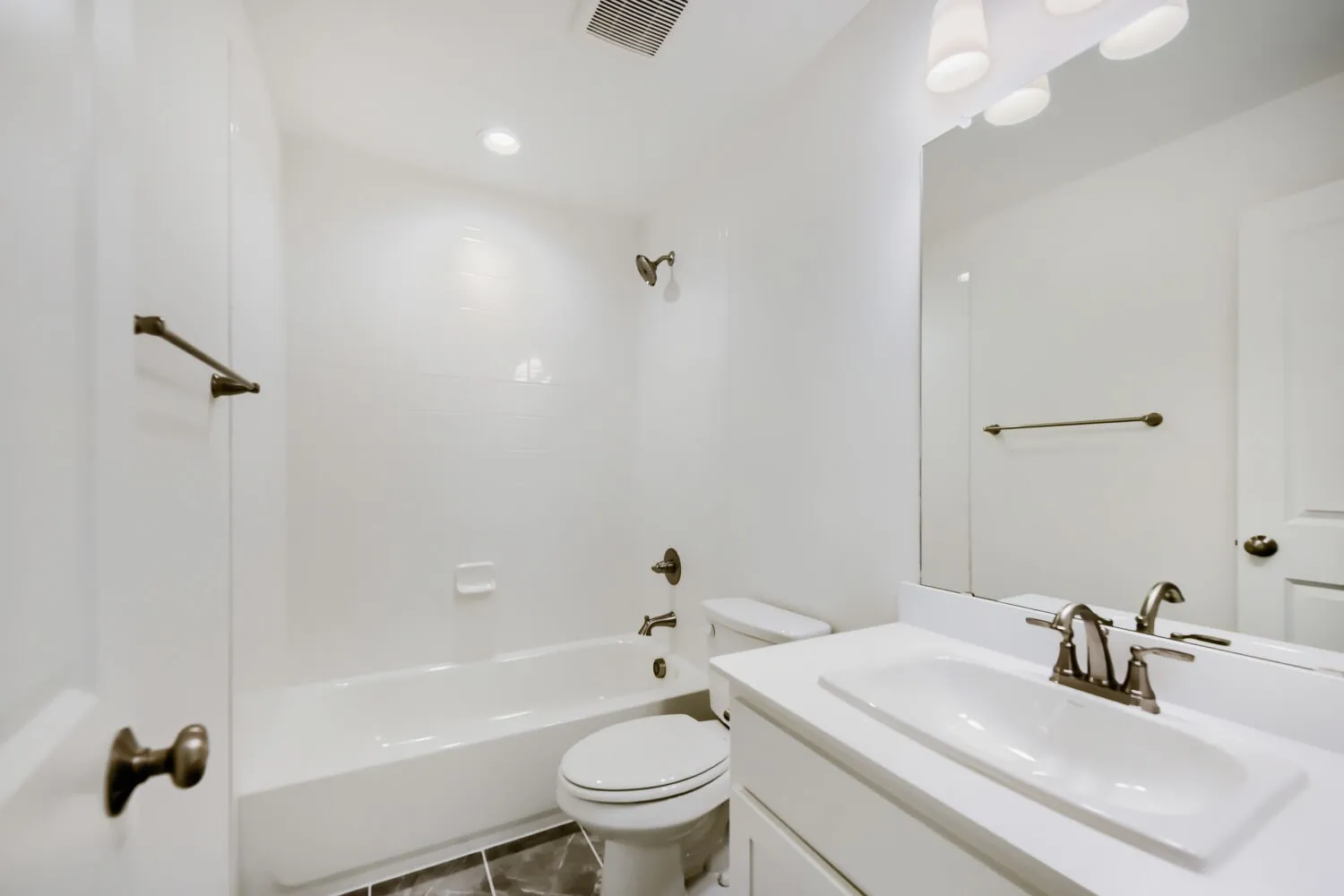 Bathroom featuring a white vanity with an integrated sink, brushed nickel faucet, and a large wall-mounted mirror