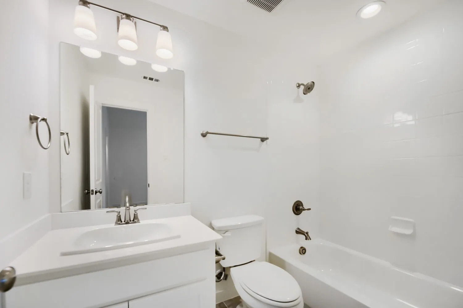 Bathroom featuring a white vanity with an integrated sink, polished chrome faucet, and a rectangular wall-mounted mirror