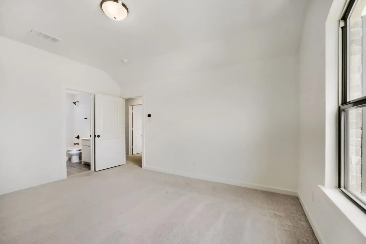 Carpeted room with a vaulted ceiling and an attached bathroom