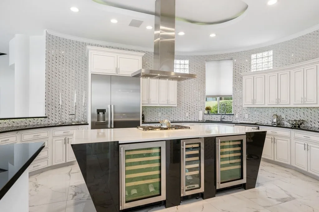 An elegant, oversized island, perfect for meal preparation, with a unique design is complemented by premium Miele and designer SMEG appliances, along with a professional-grade Viking refrigerator-perfectly crafted for gourmet gatherings.