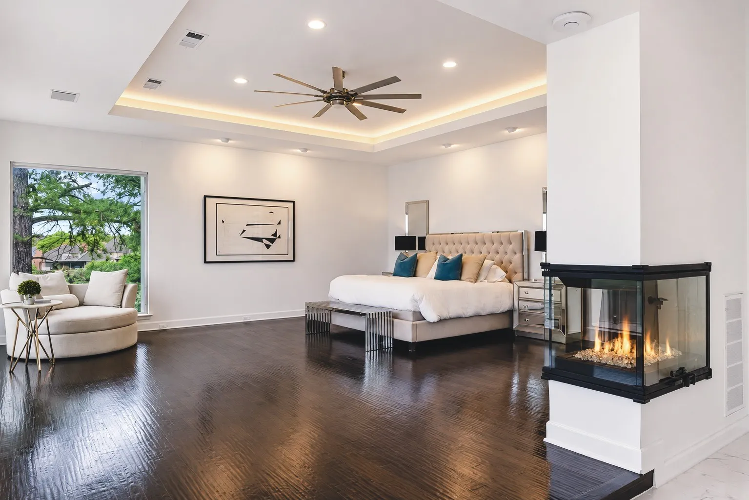 The grand primary suite exudes elegance, featuring a custom double-side fireplace, rich hardwood floors, and spacious layout-all complemented by panoramic lake views that enhance the tranquil retreat.