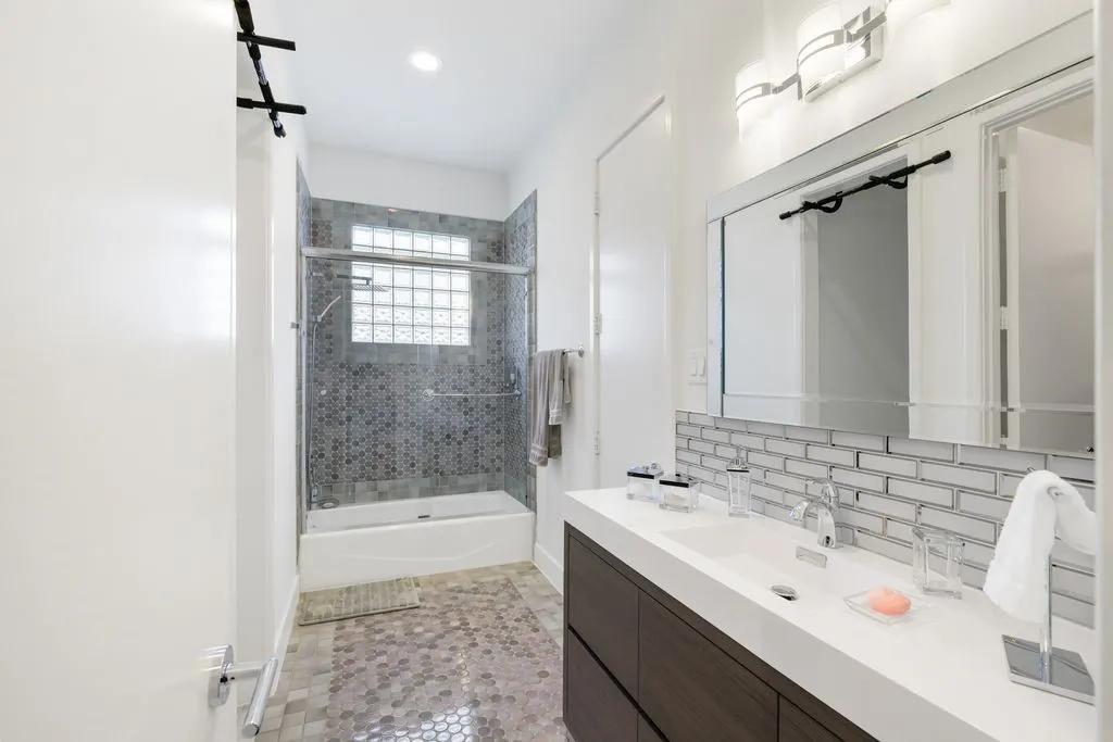 This bathroom offers a sleek combination of a soaking tub and glass-enclosed shower, providing both versatility and comfort.