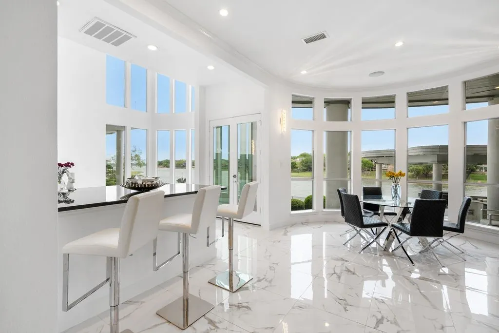 This open floor plan seamlessly connects different areas, all framed by continuous wall of windows that showcase panoramic views of the water.