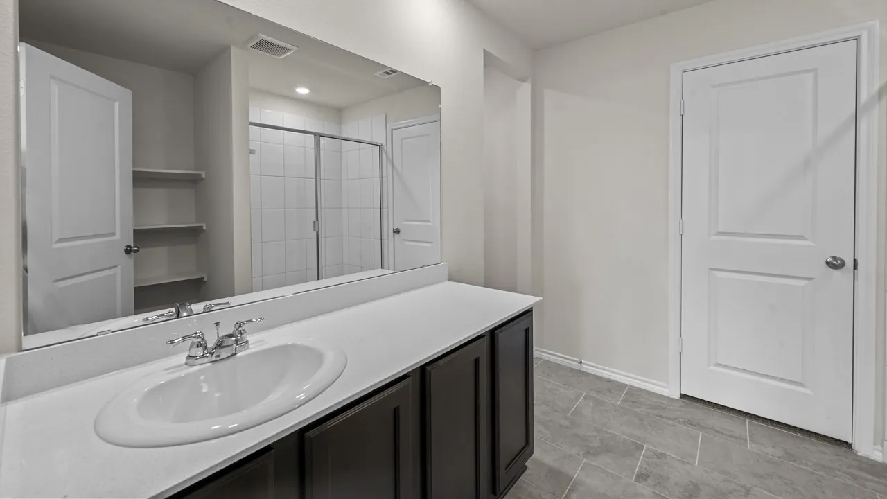Contemporary vanity with a white oval undermount sink, chrome faucet, and dark wood cabinetry