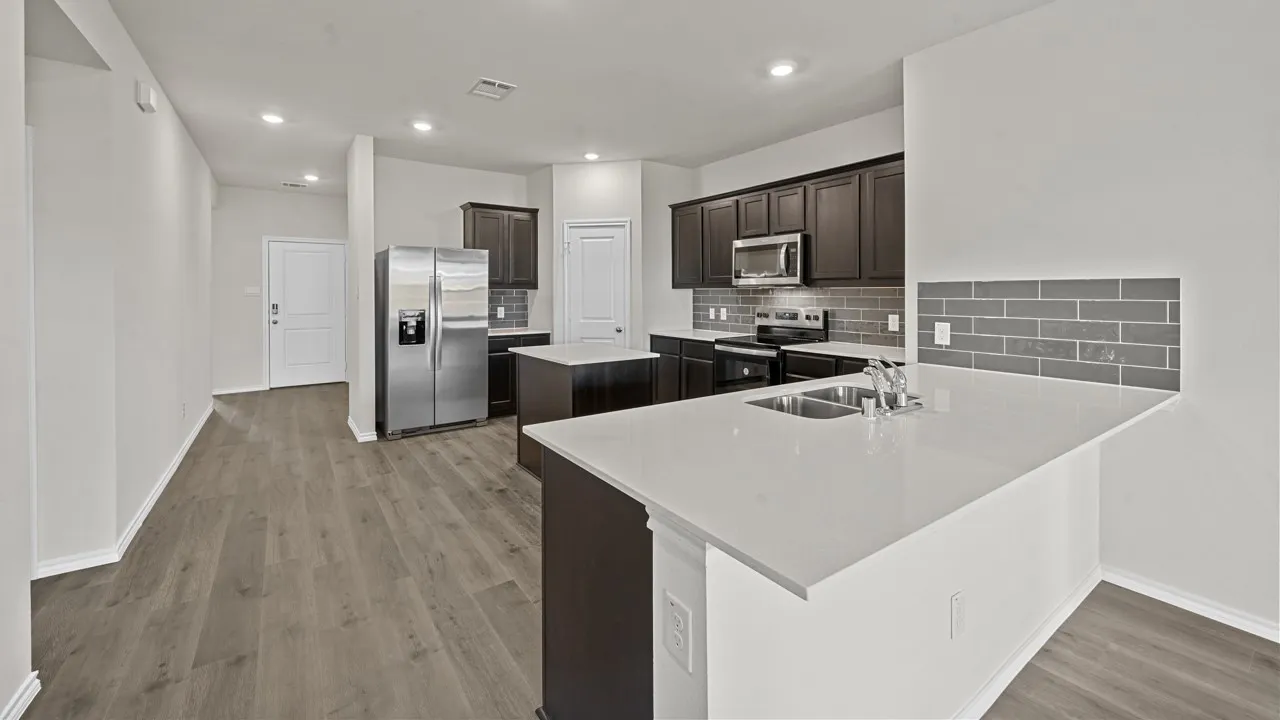 Open-concept kitchen featuring dark wood cabinetry, stainless steel appliances, white countertops, a subway tile backsplash, and wood-finish flooring