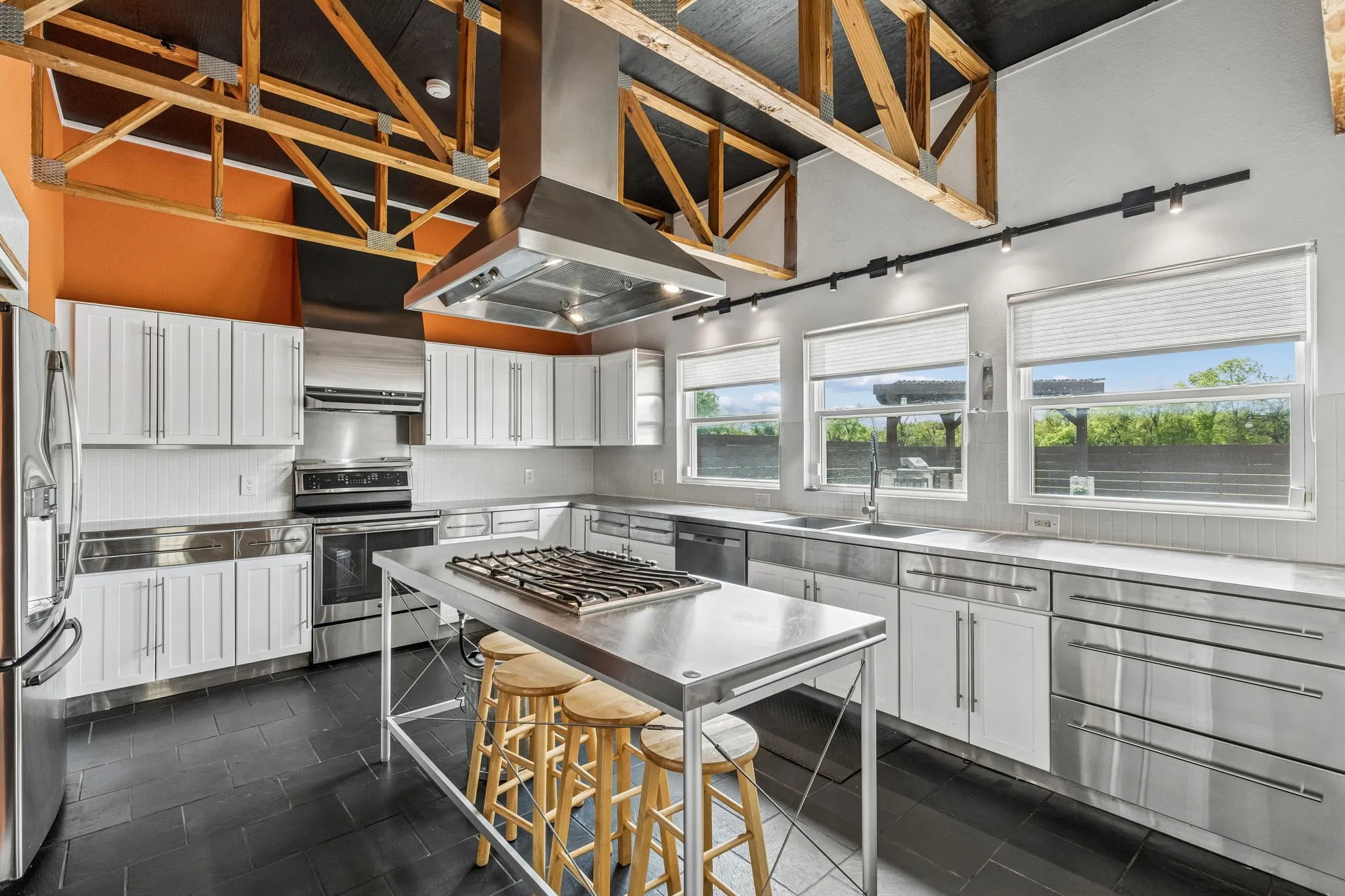 Custom kitchen with electric oven, dishwasher, refrigerator and tile flooring.  The island is mobile and there is a gas tank underneath for the center grill.  Professionally installed commercial vent a hood above.