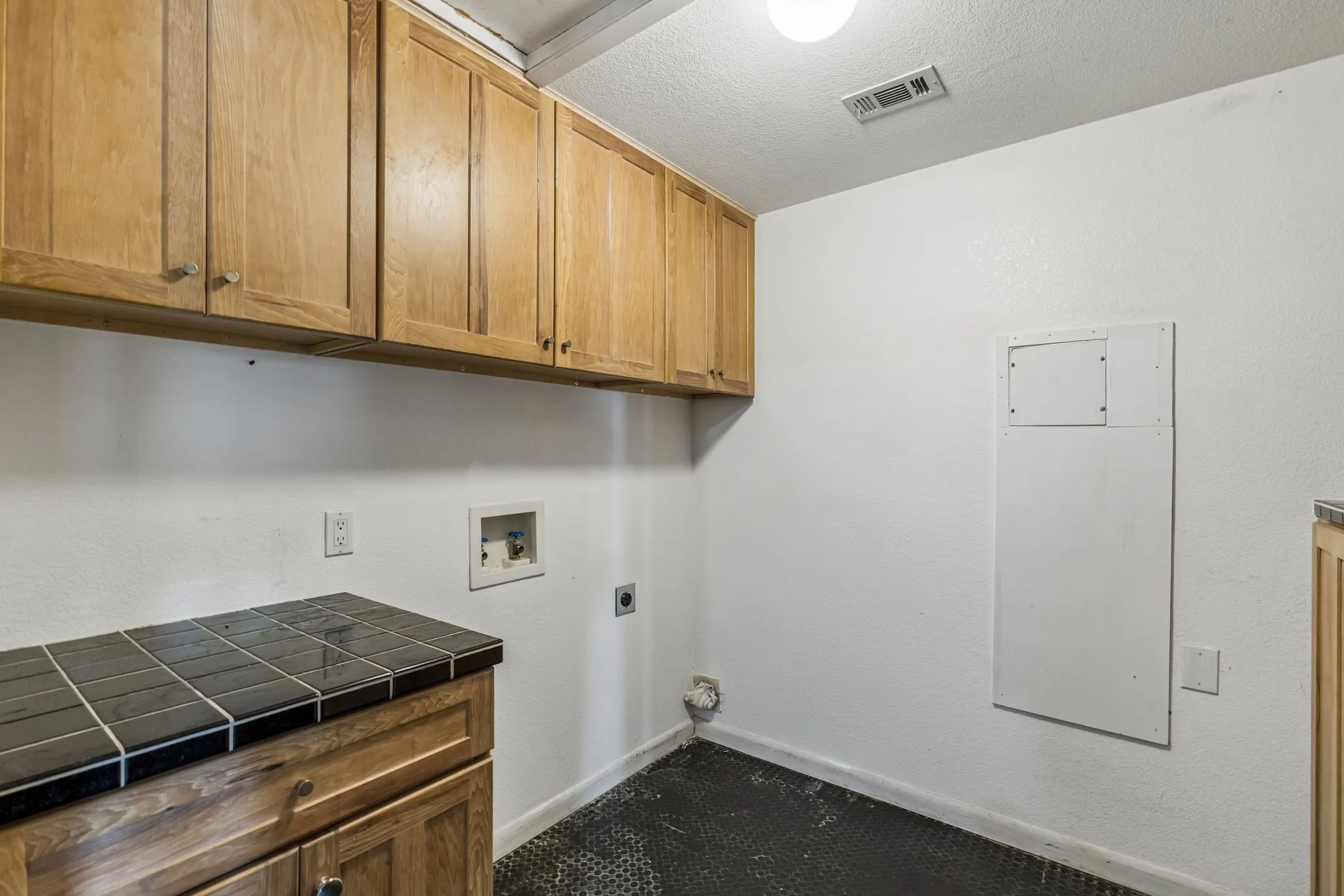 Separate full size washer and dryer laundry room near the kitchen with tile flooring. and built in cabinets.