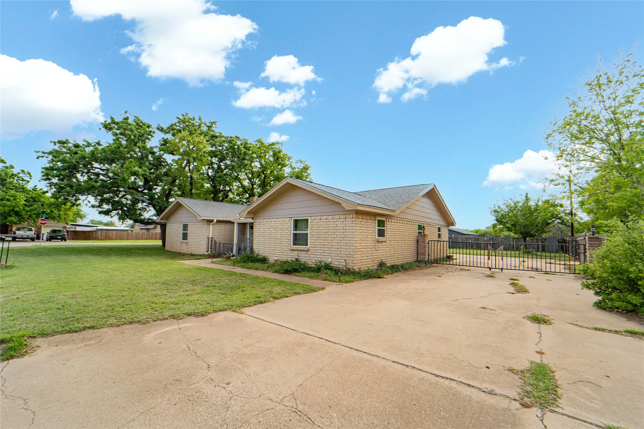 View of front of home with driveway, brick siding, and a gate