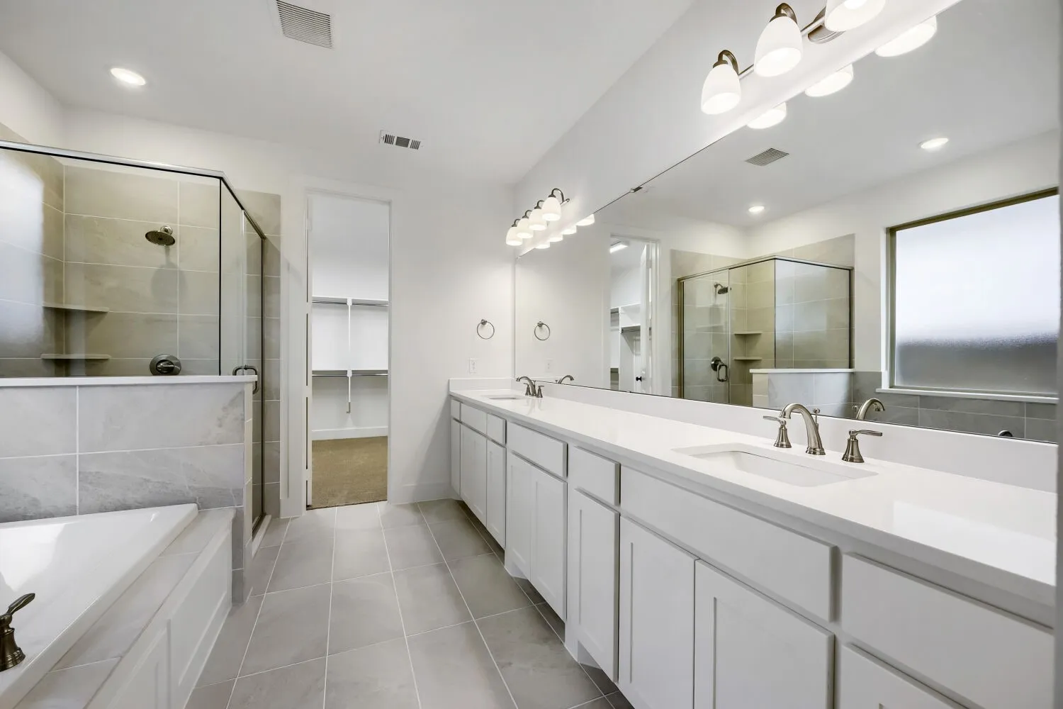 Double vanity with white cabinetry and integrated sinks set beneath a full-width mirror
