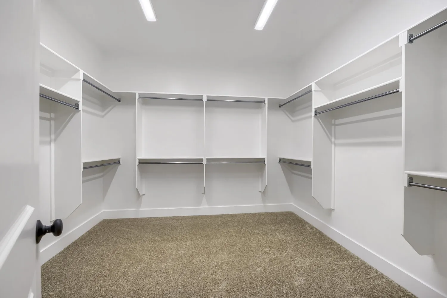 Spacious walk-in closet featuring white built-in shelving, multiple hanging rods, and recessed lighting