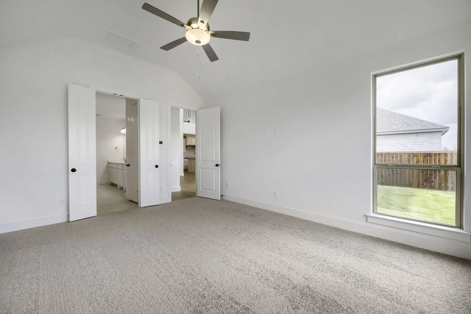 Spacious room featuring vaulted ceilings, a contemporary ceiling fan, and carpeted flooring