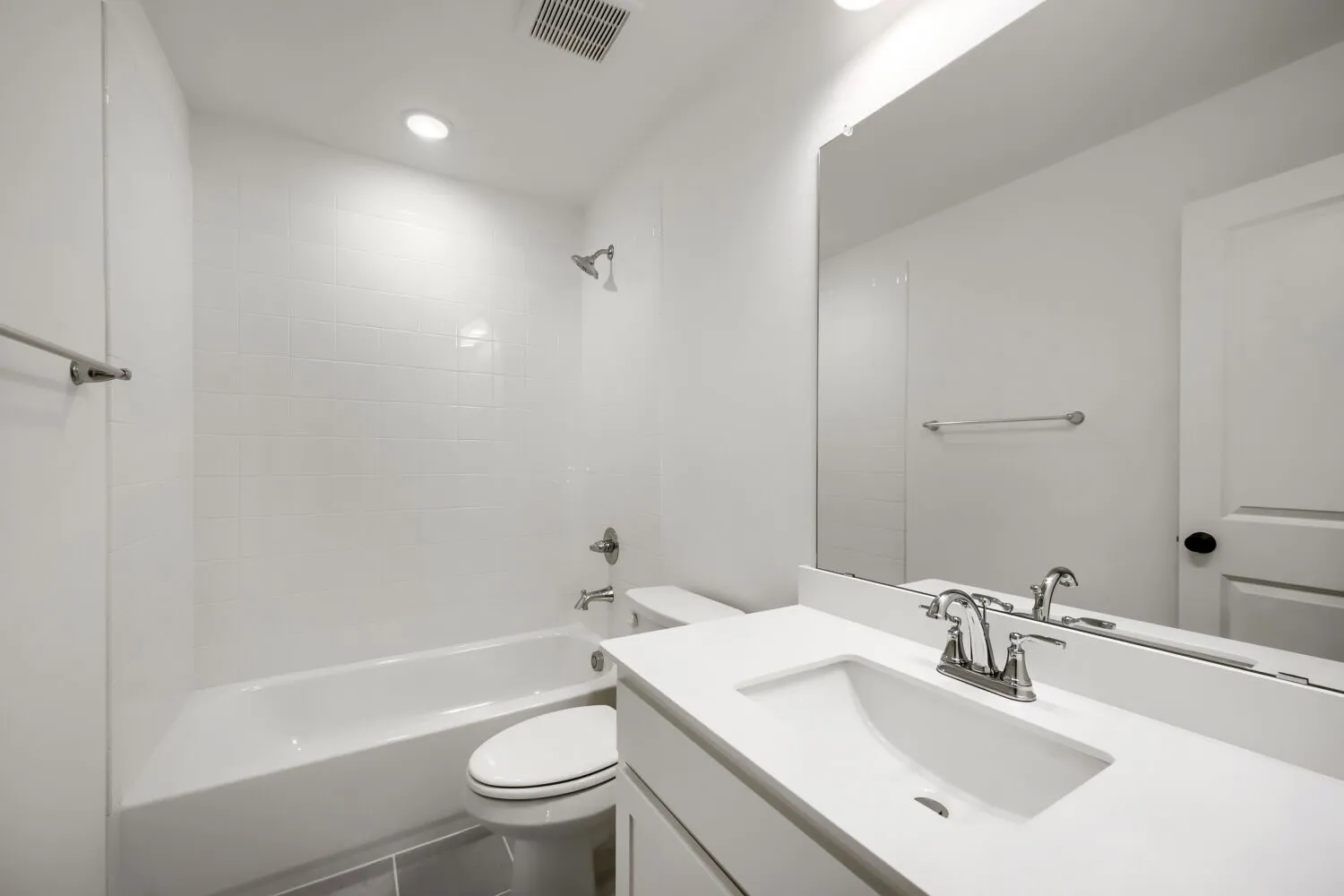 Bathroom featuring a white subway tile shower surround, a built-in bathtub, and a single vanity with a white countertop and undermount sink