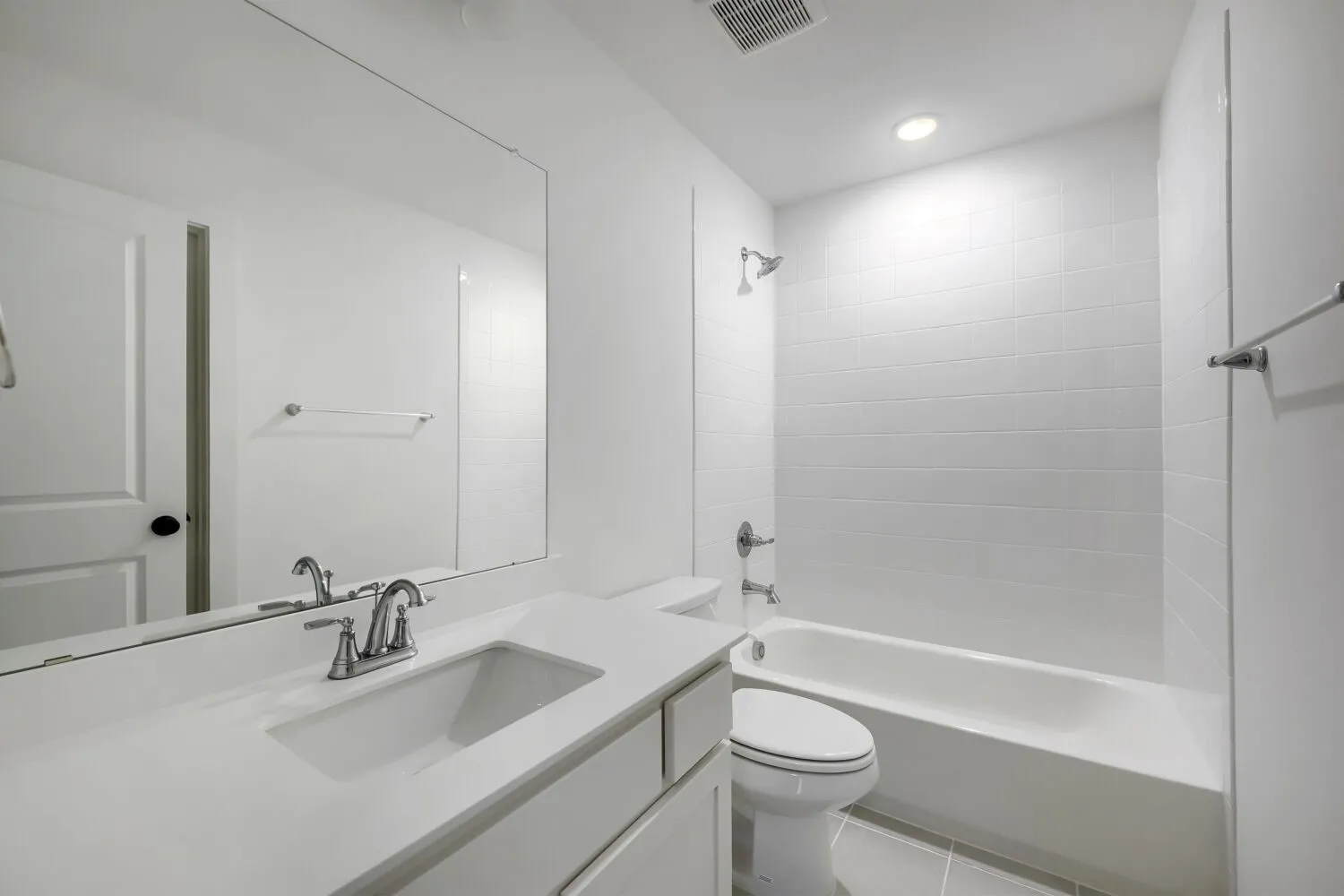 Bathroom featuring a white vanity with integrated sink, rectangular mirror, and chrome fixtures