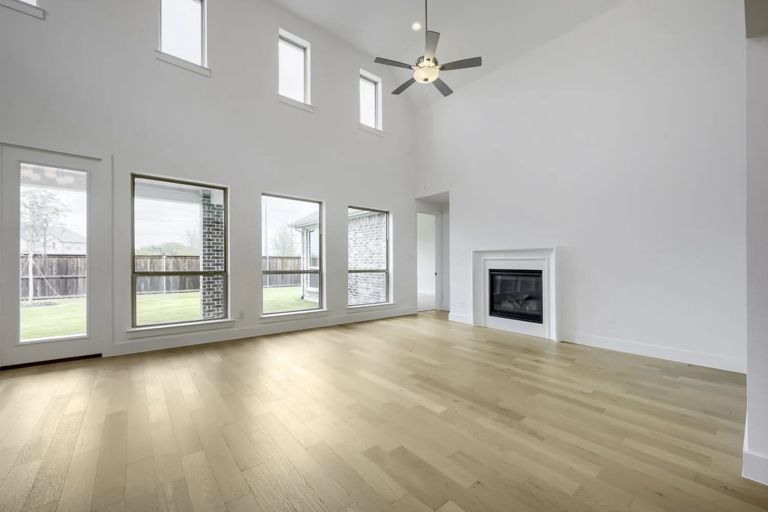 Spacious living area featuring high ceilings, wood-finish flooring, and multiple large windows