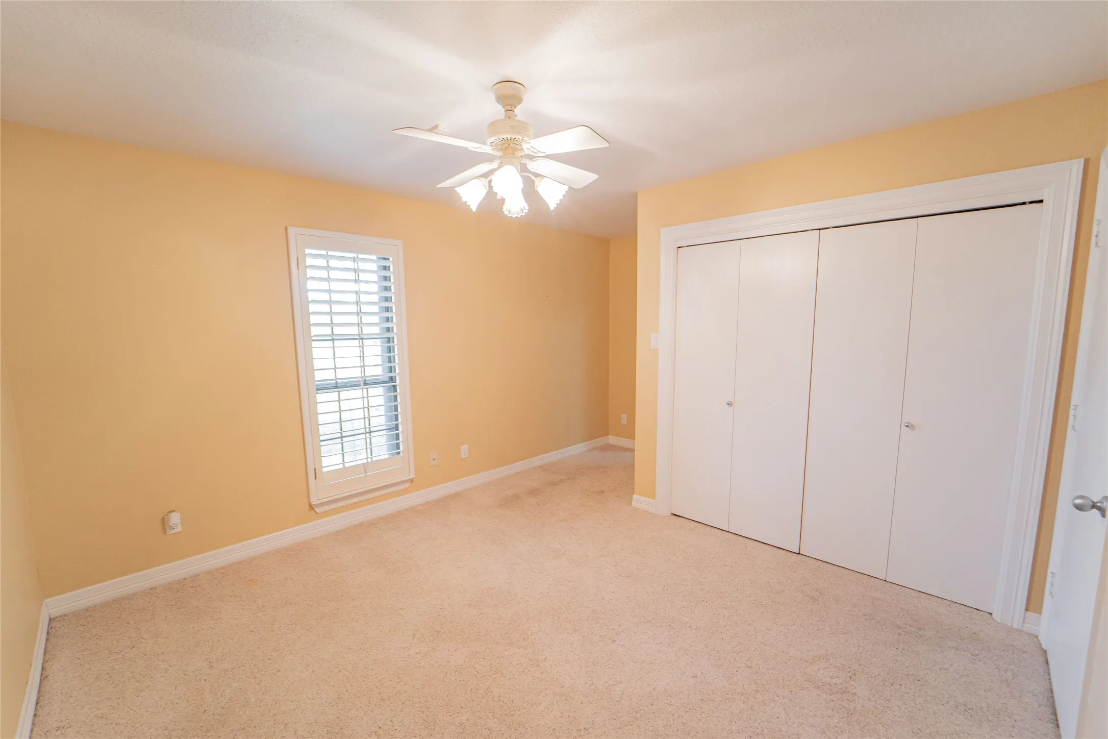 Unfurnished bedroom with a closet, light colored carpet, and ceiling fan