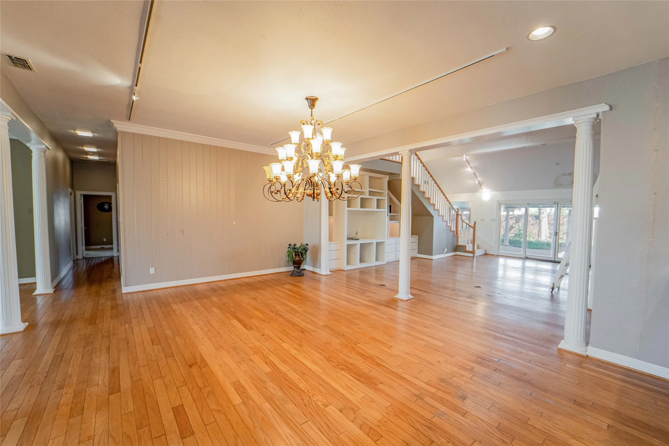Dining area featuring decorative columns, light wood-style flooring, and hanging lights