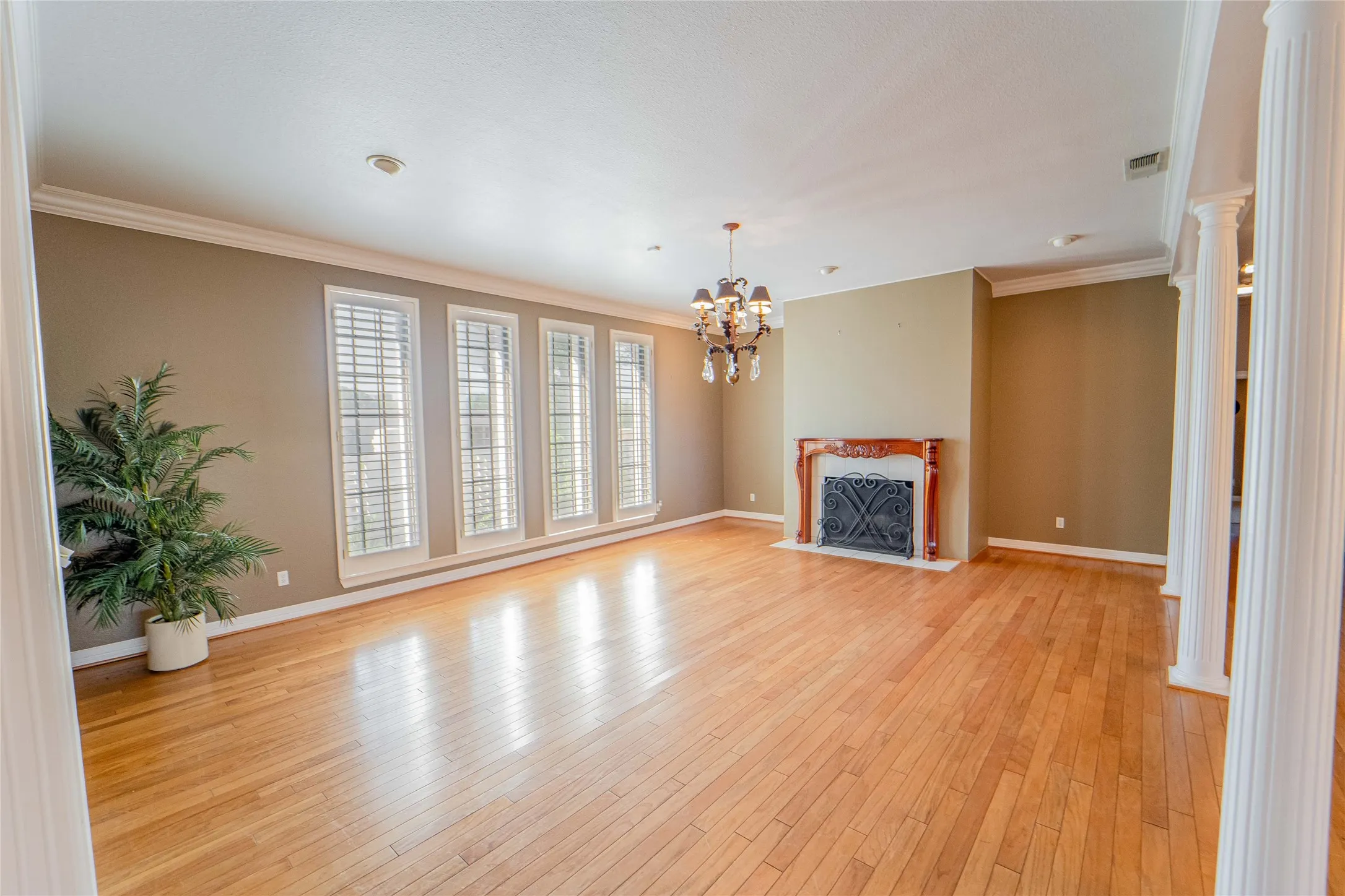 Living room with hanging lights, light wood-style flooring, and ornamental molding