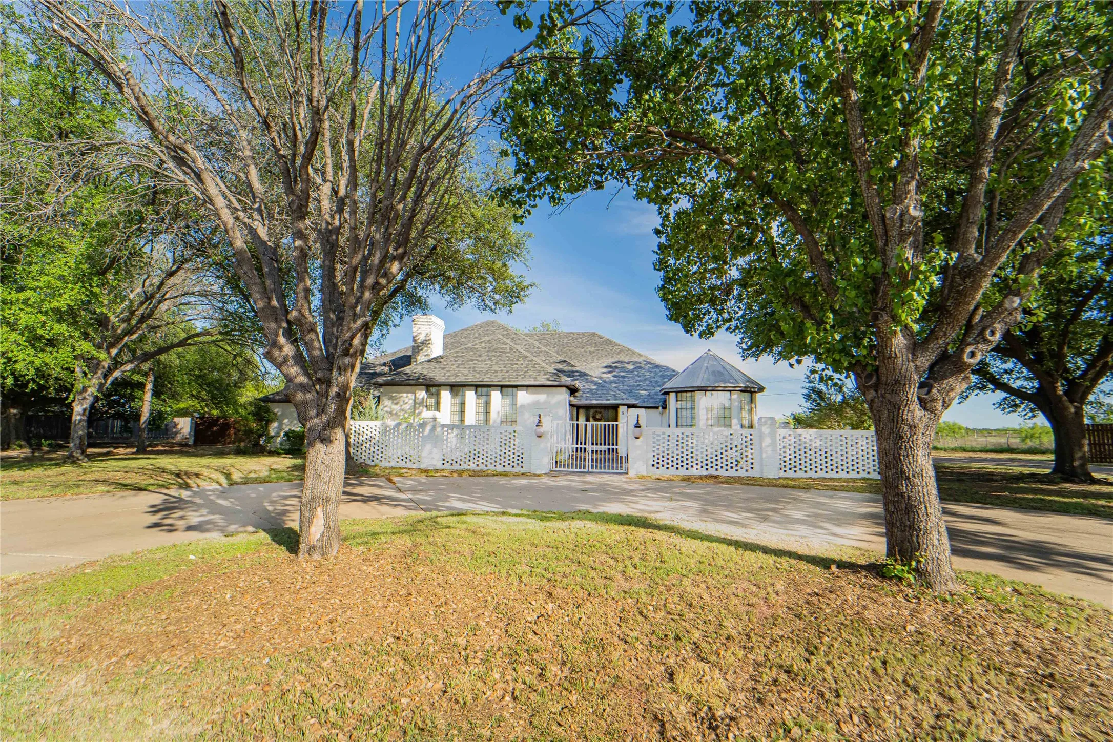 View of front of property with a fenced front yard, a gate, a chimney, and driveway