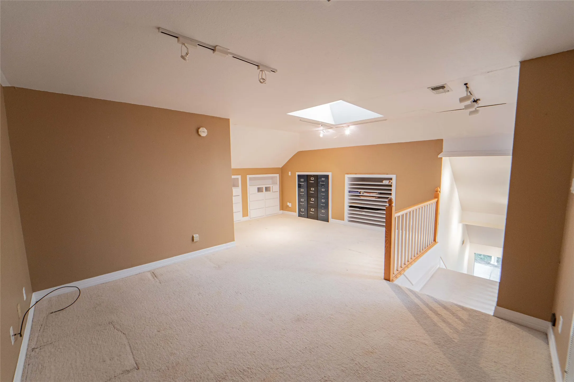 Office space with lofted ceiling, built in features, light carpet, and a skylight
