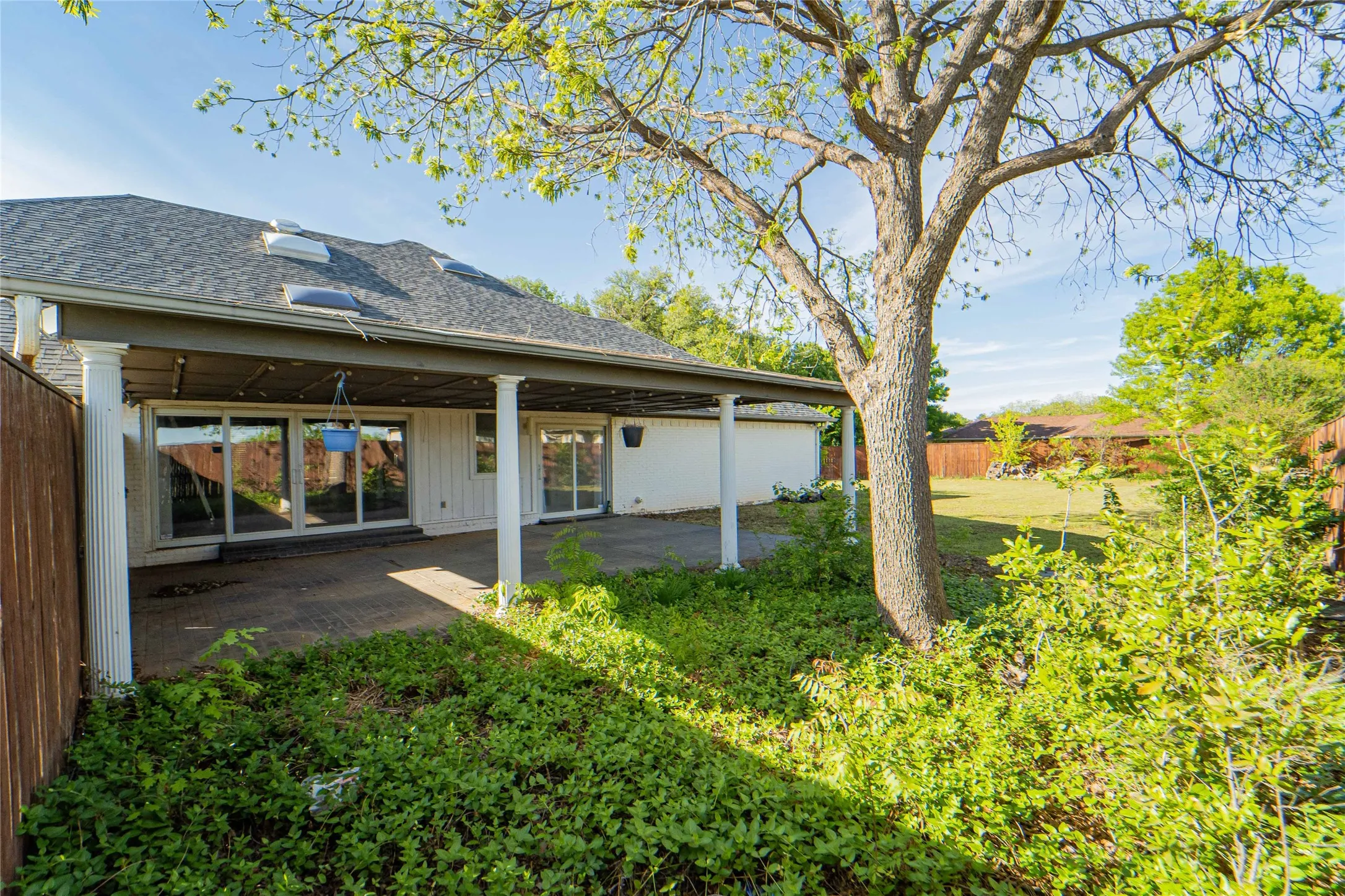 Rear view of property with a shingled roof and a patio area
