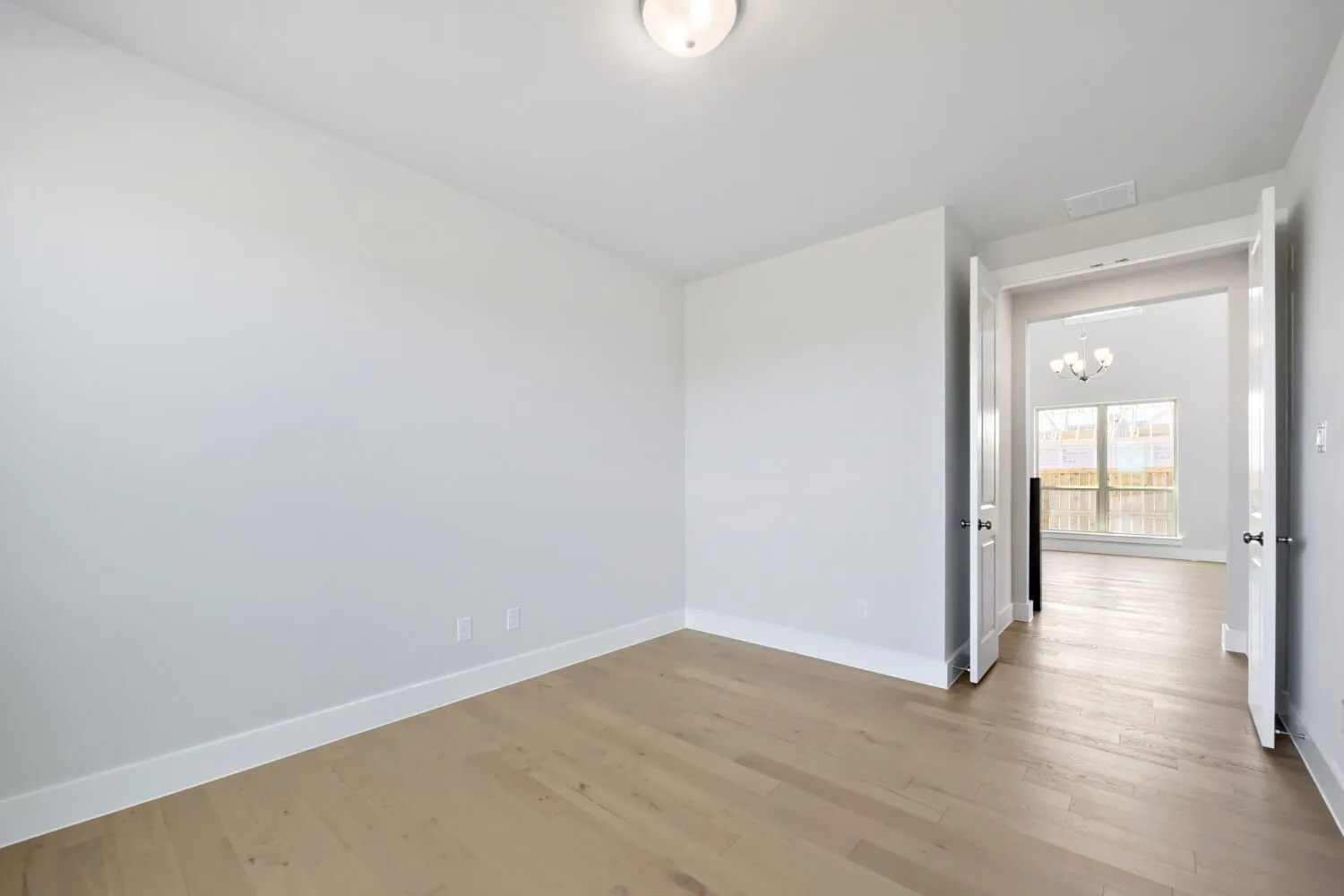 Room with wood-finish flooring, white baseboards, and a flush-mount ceiling light