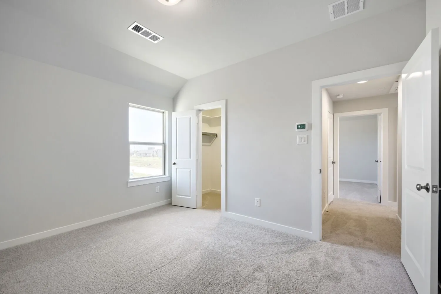 Bright room with vaulted ceiling, light gray carpeting, and white trim