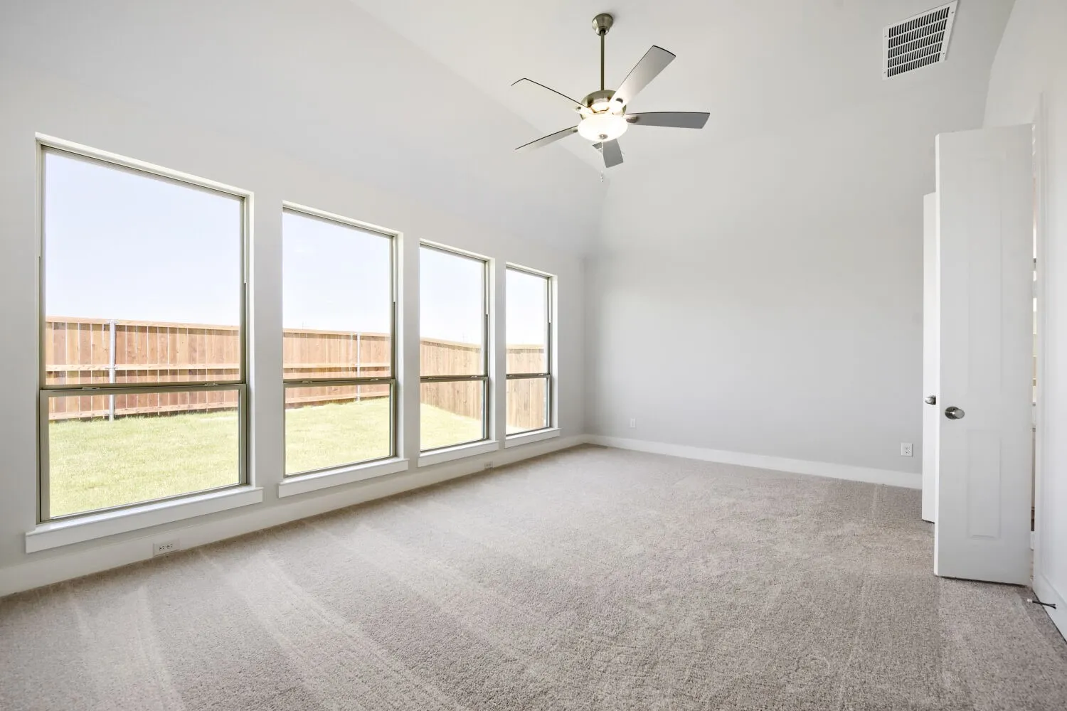 Spacious room featuring vaulted ceilings, a contemporary ceiling fan, and light gray wall paint
