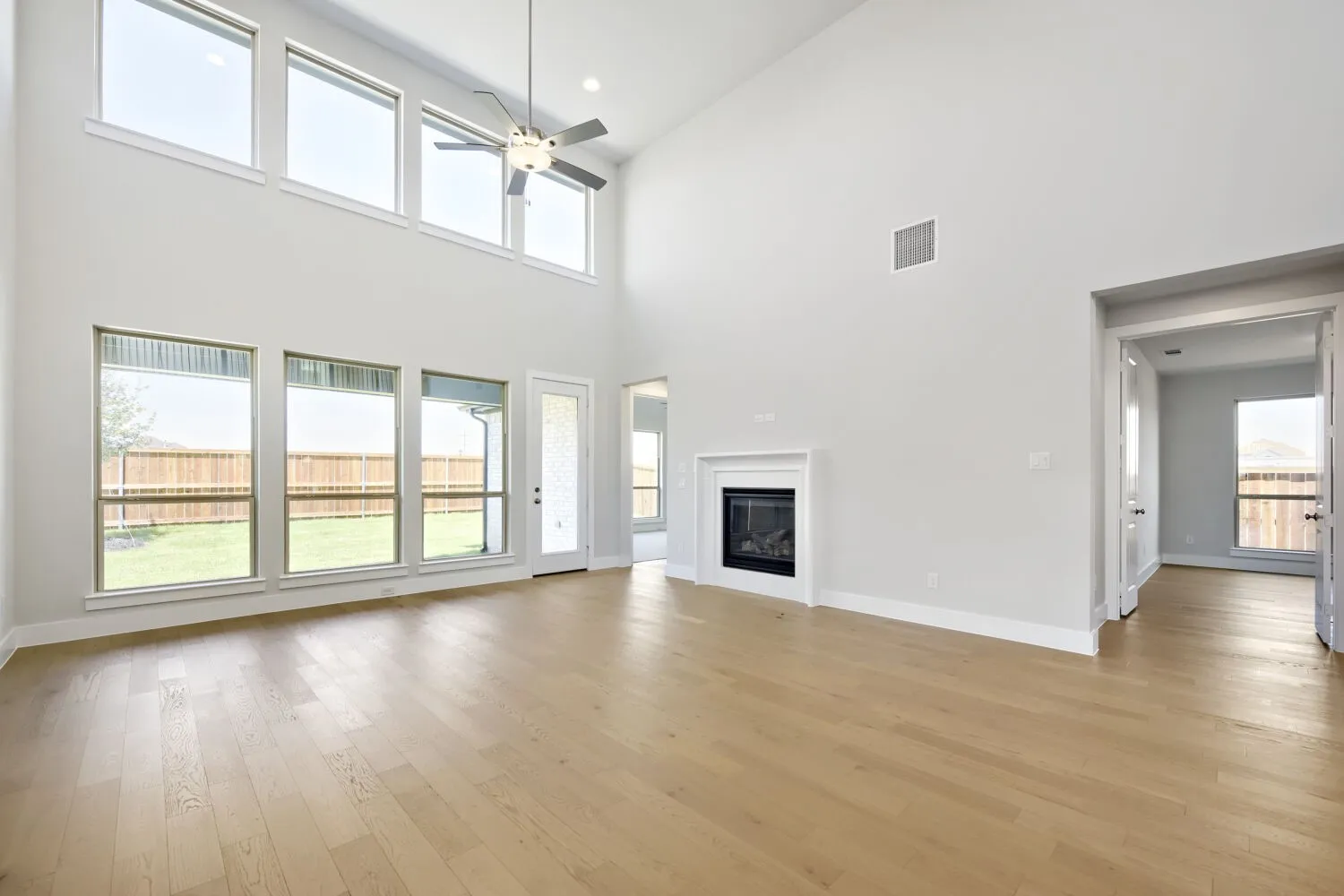 High ceilings defining a spacious room featuring a floor-to-ceiling fireplace and an abundance of natural light