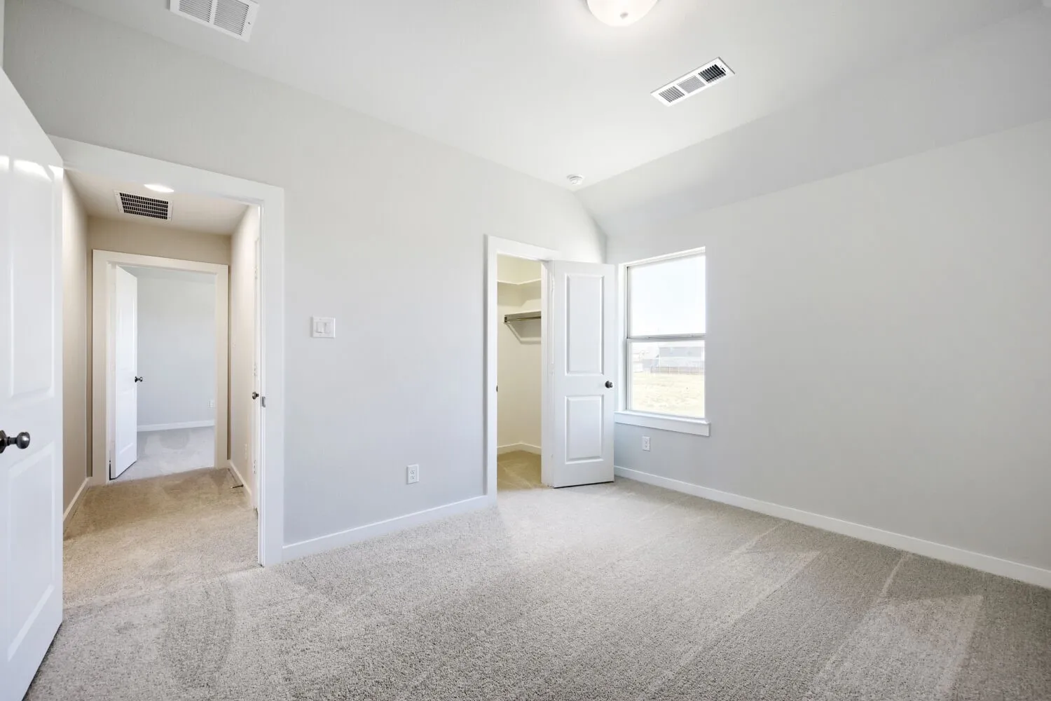 Carpeted room with vaulted ceiling and a rectangular window