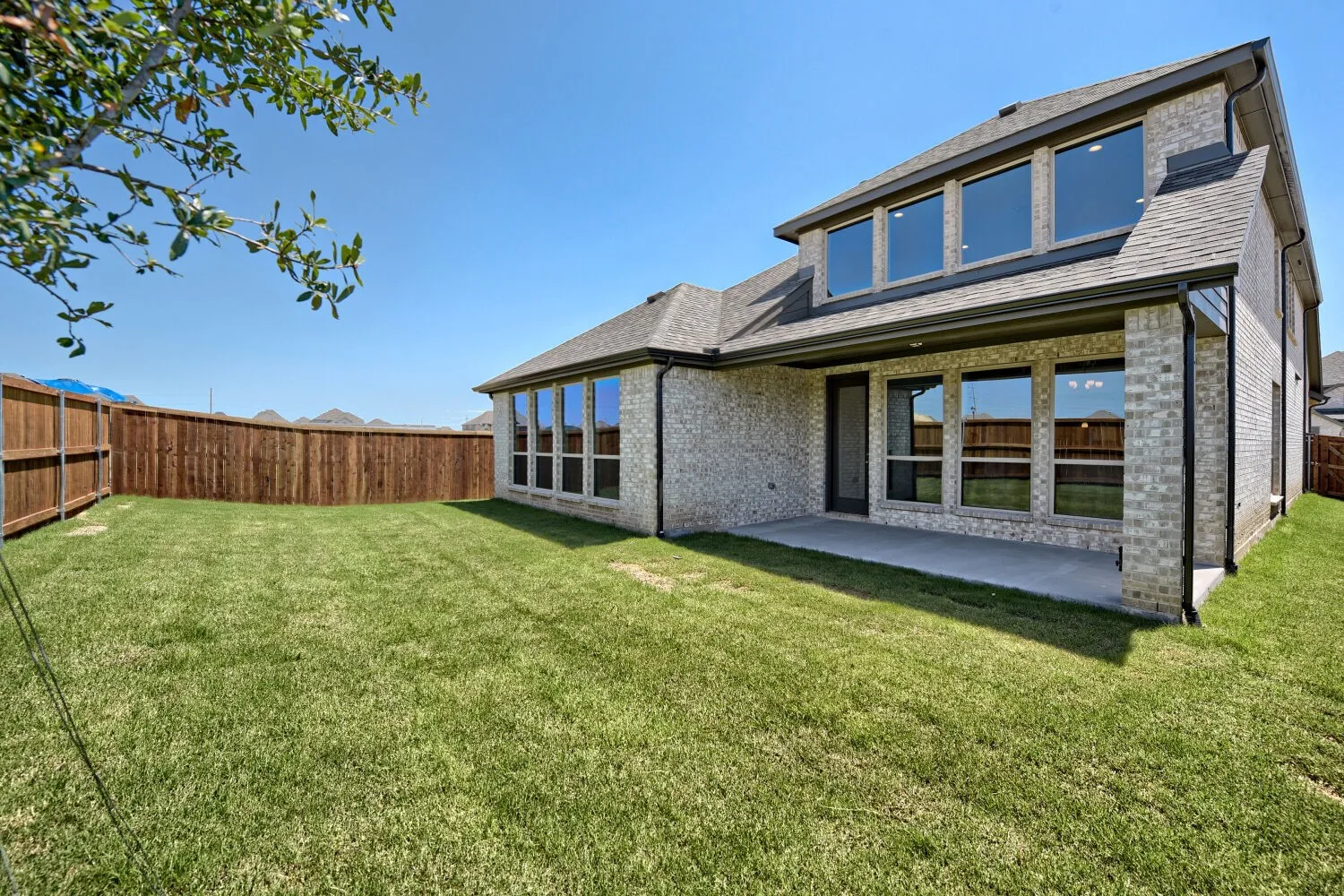 Spacious backyard with a covered patio, extensive lawn, and full privacy fencing
