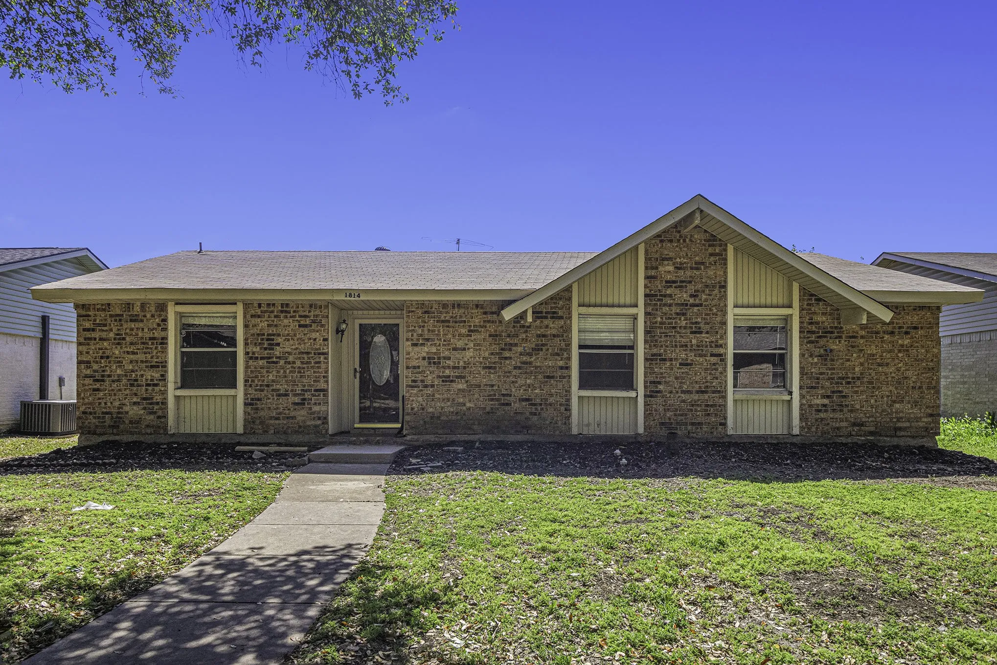 Ranch-style house featuring central air condition unit and a front lawn