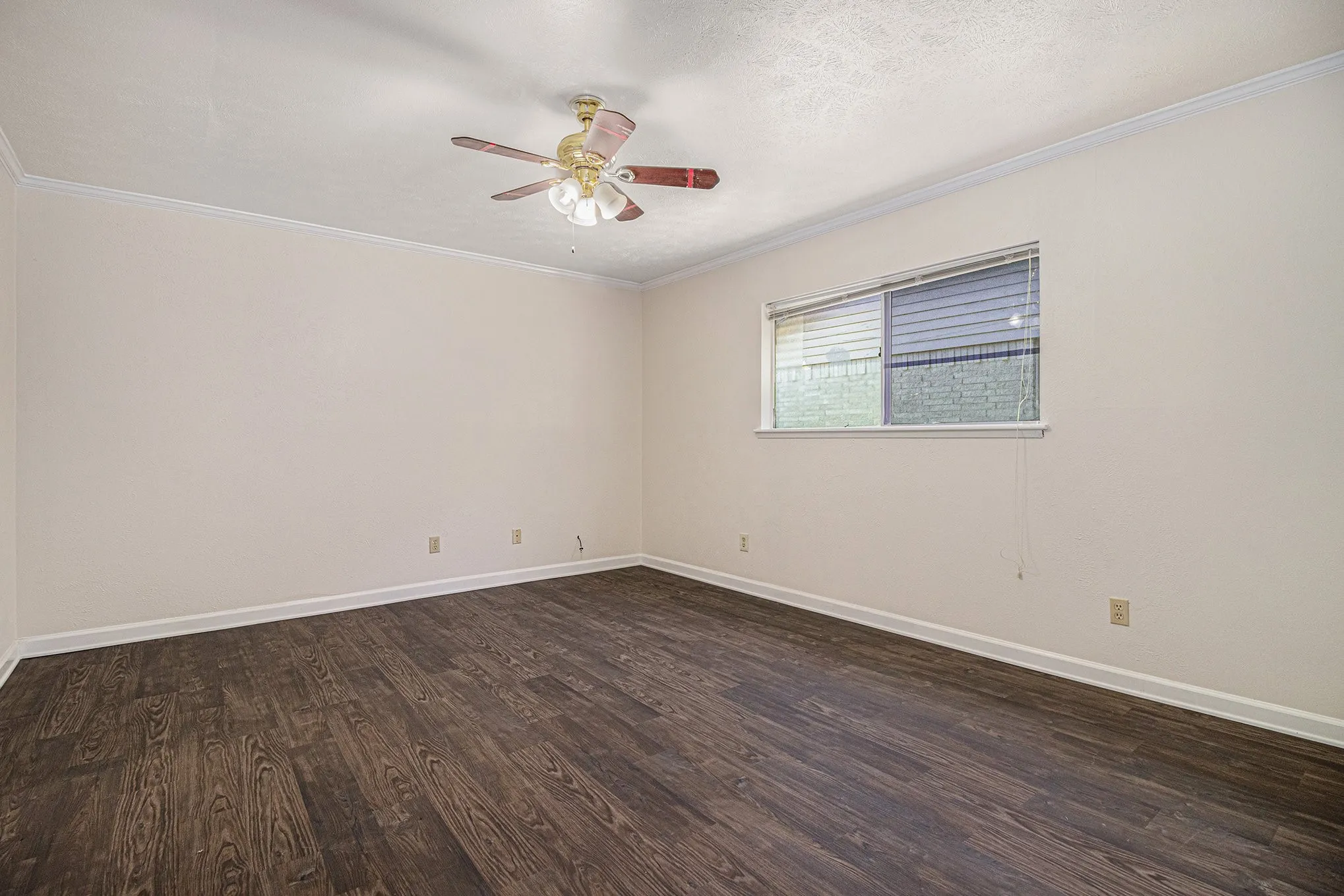 Empty room with ornamental molding, dark hardwood / wood-style flooring, and ceiling fan