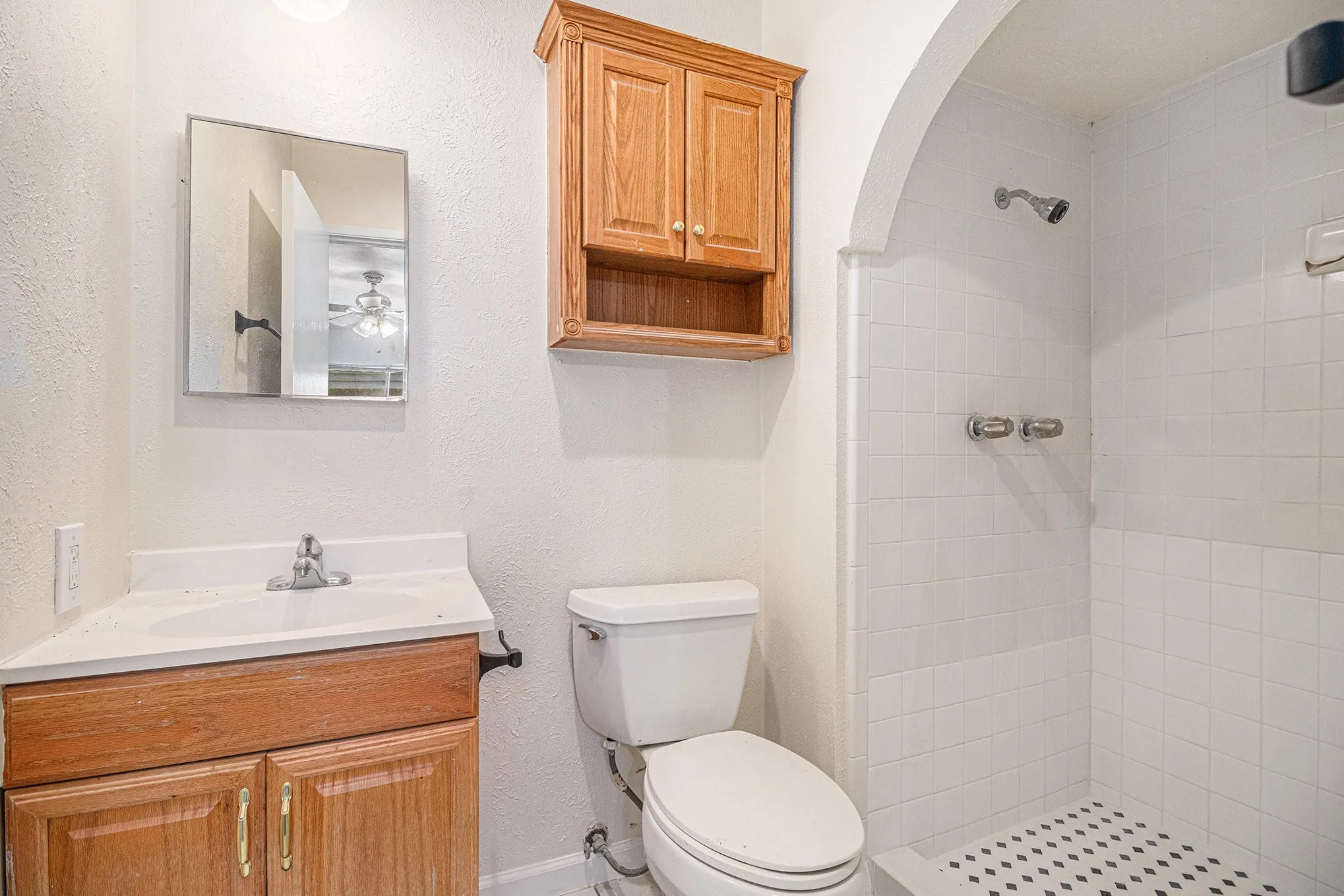 Bathroom featuring a tile shower, oversized vanity, ceiling fan, and toilet