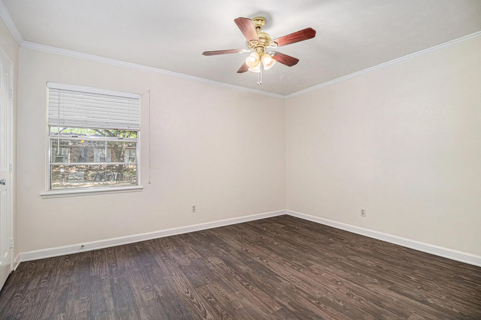 Empty room featuring crown molding, dark hardwood / wood-style flooring, and ceiling fan
