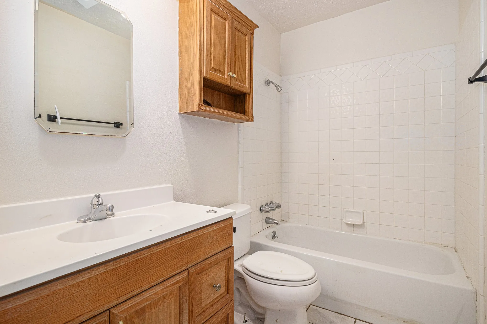 Full bathroom with tiled shower / bath, toilet, tile floors, and large vanity