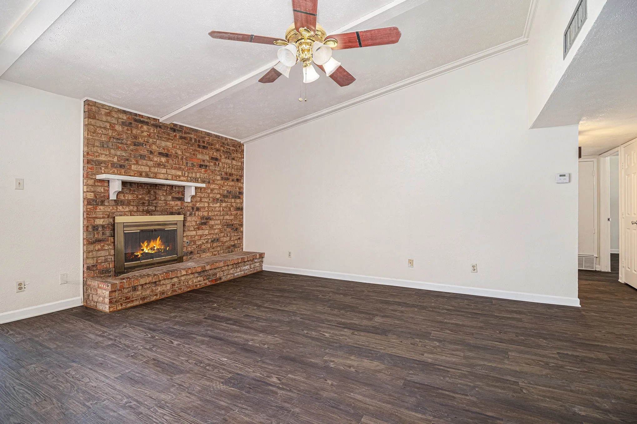 Unfurnished living room with ceiling fan, a textured ceiling, a fireplace, and dark hardwood / wood-style floors