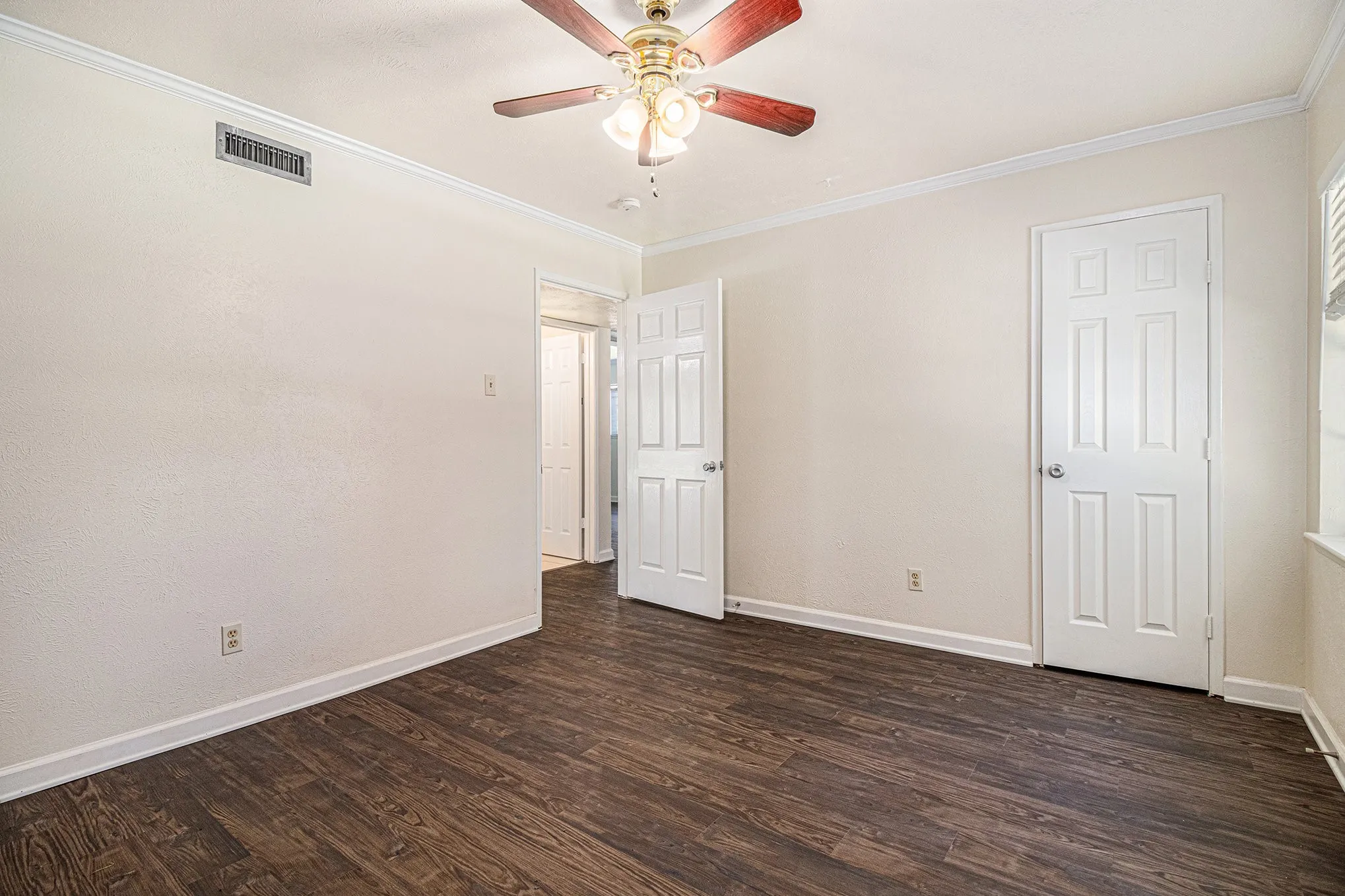 Unfurnished room featuring dark hardwood / wood-style flooring, ceiling fan, and ornamental molding