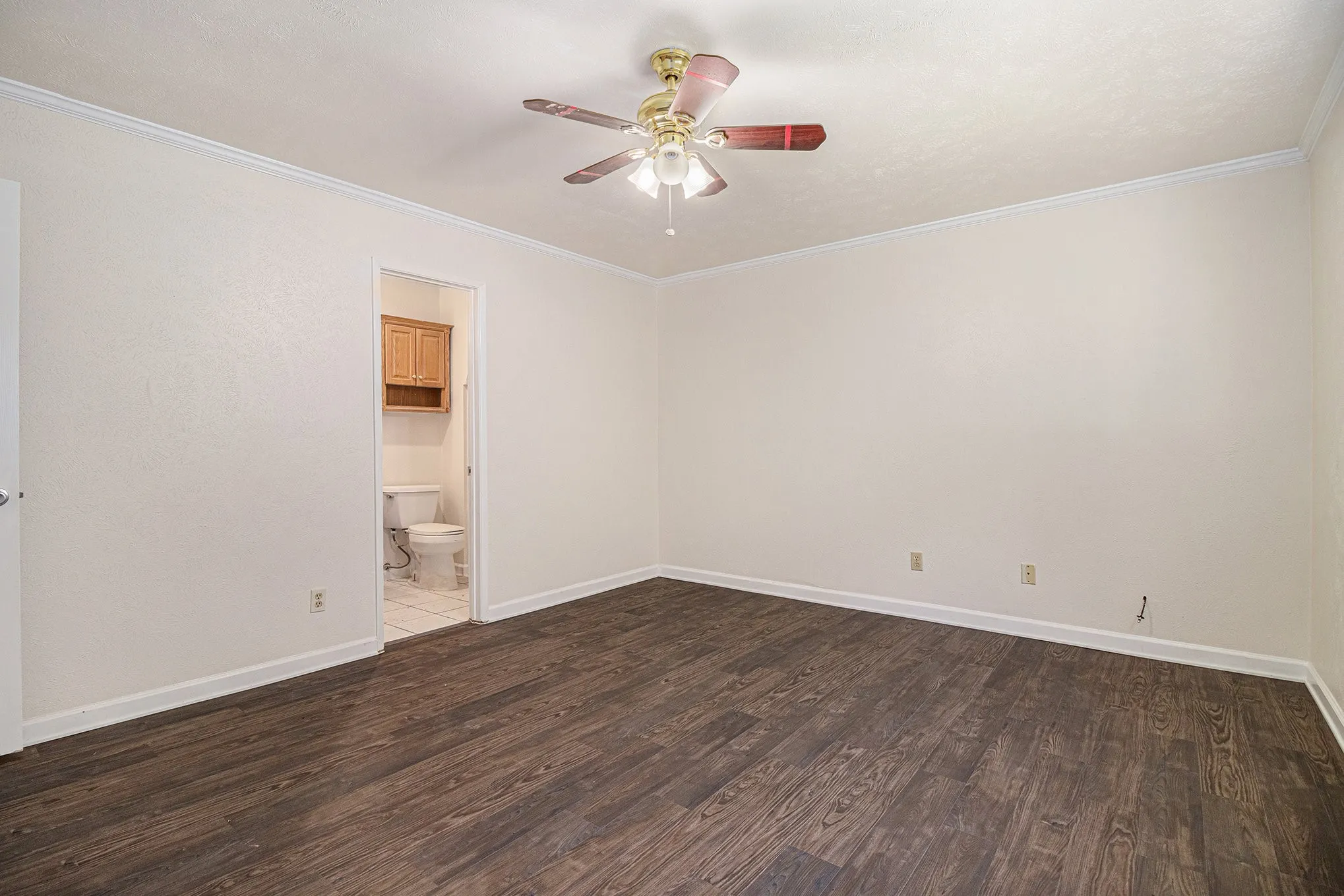 Spare room with ceiling fan, crown molding, and dark wood-type flooring