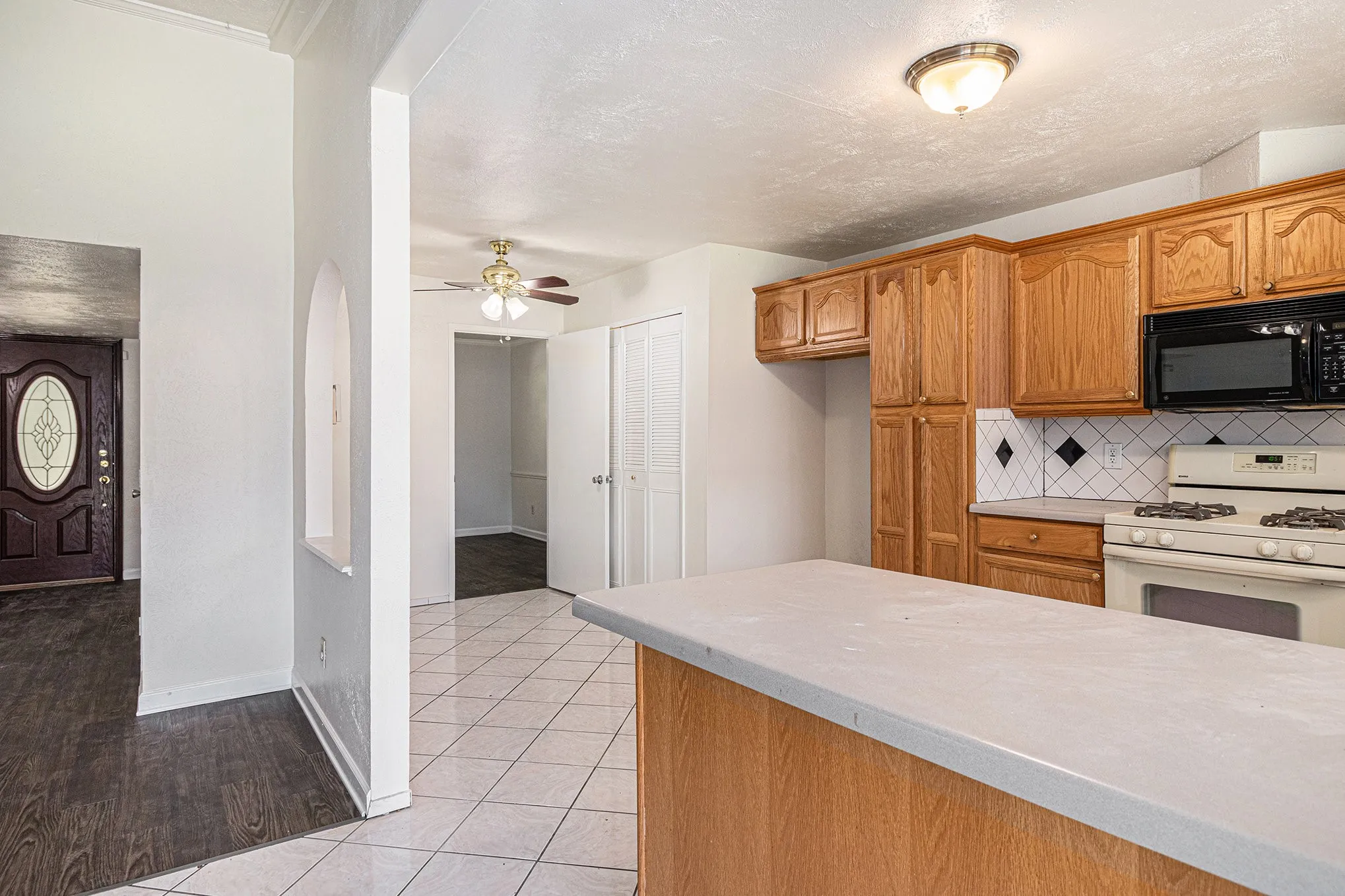 Kitchen featuring light hardwood / wood-style flooring, ceiling fan, backsplash, and white gas range oven