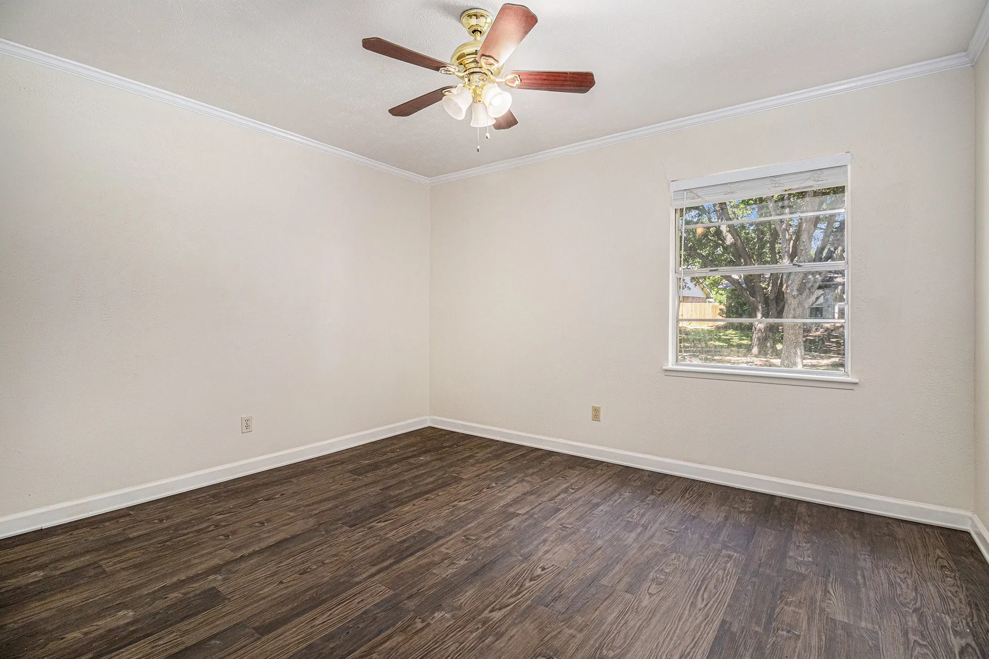 Spare room with crown molding, ceiling fan, and dark wood-type flooring