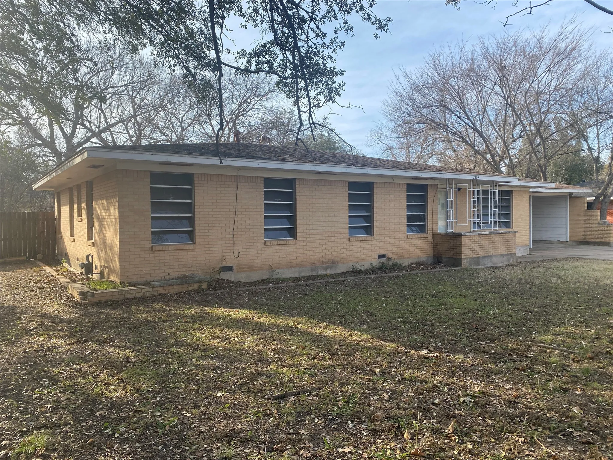 View of front of house featuring brick siding, crawl space, and an attached carport