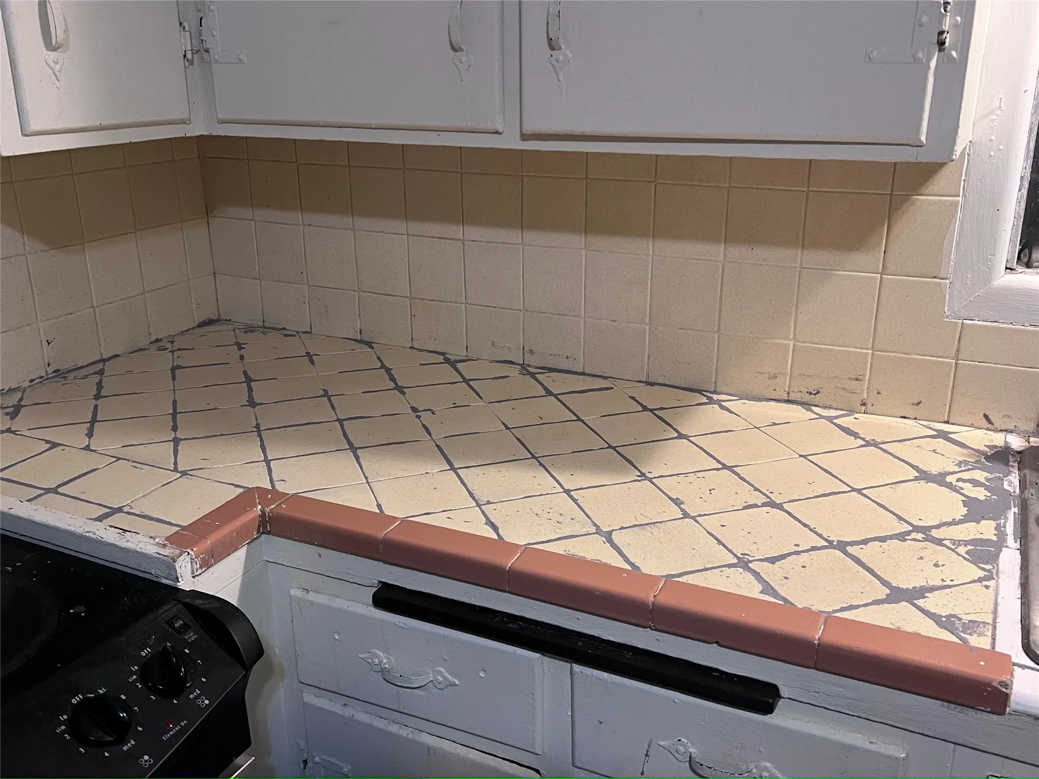 Detailed view of tile counters, backsplash, and white cabinets