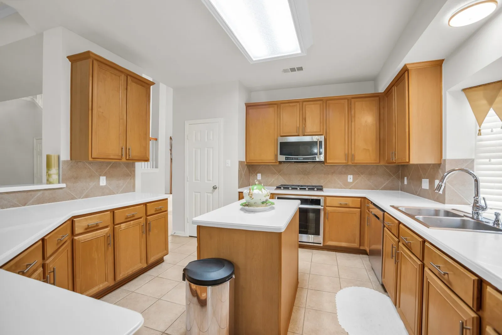 Kitchen with light countertops, wood finish cabinetry, and light tile patterned floors