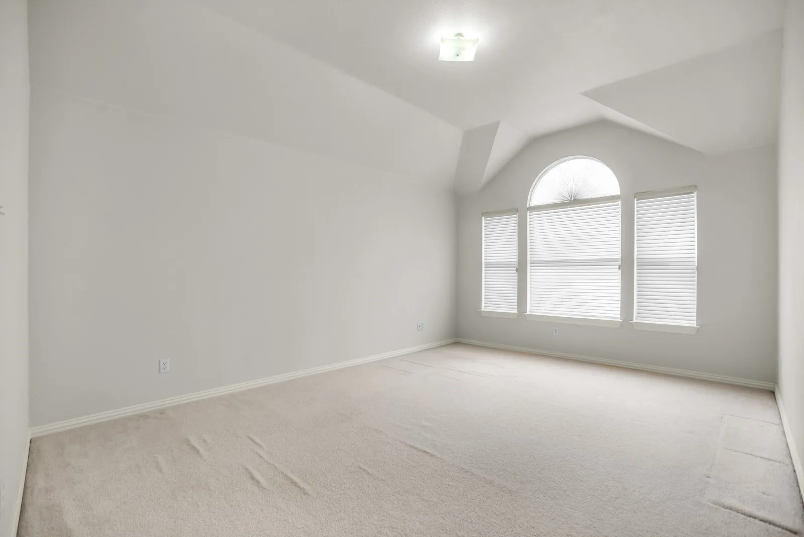 Unfurnished room featuring light colored carpet and lofted ceiling