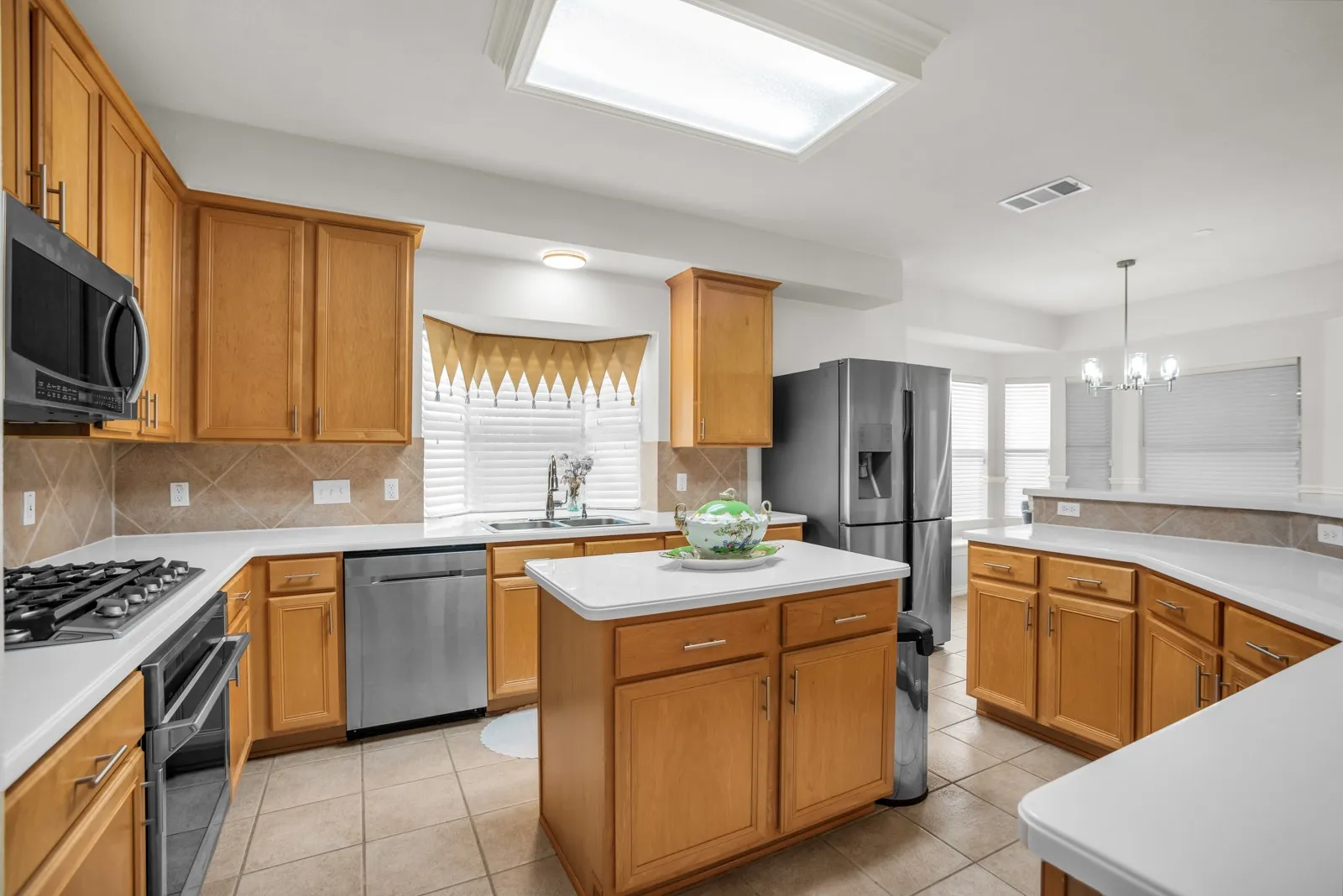 Kitchen with a kitchen island, stainless steel appliances, light countertops, and light tile patterned flooring