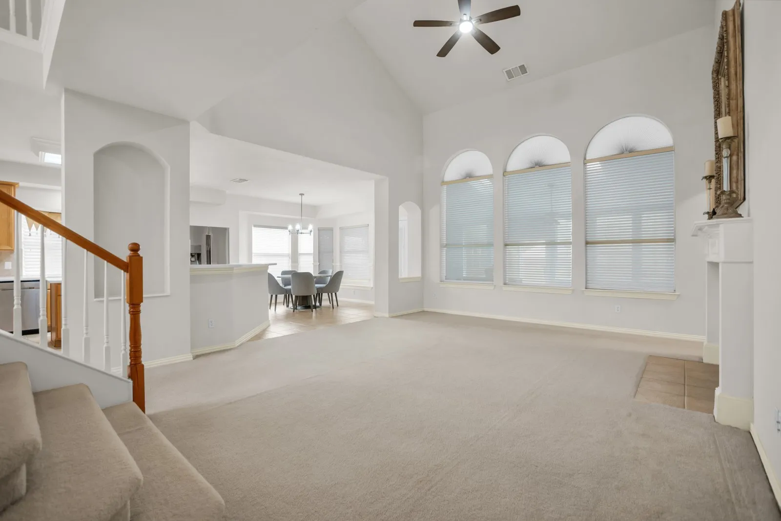 Living room with lofted ceiling, ceiling fan, and light colored carpet