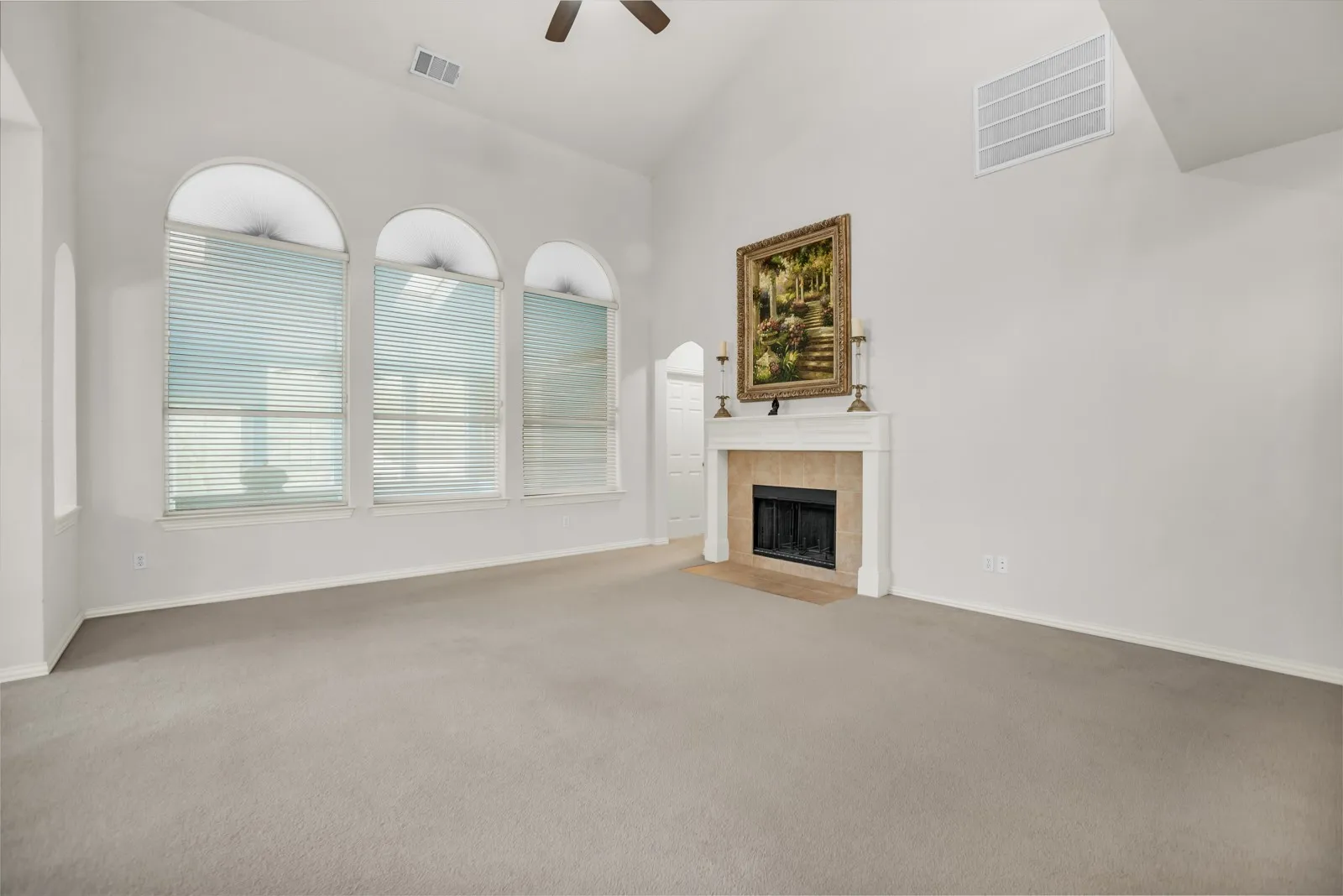 Unfurnished living room featuring vaulted ceiling, ceiling fan, light carpet, and a tiled fireplace
